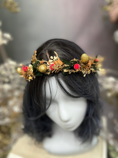 Golden Christmas flower wreath with cinnamon sticks and evergreen branches and with a ribbon at the back to tie